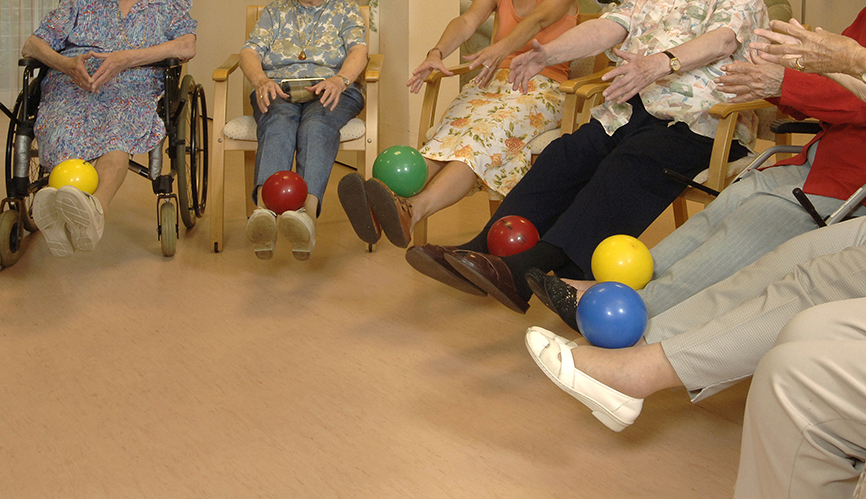 Foto von Senioren bei Bewegungsspielen mit bunten Bällen